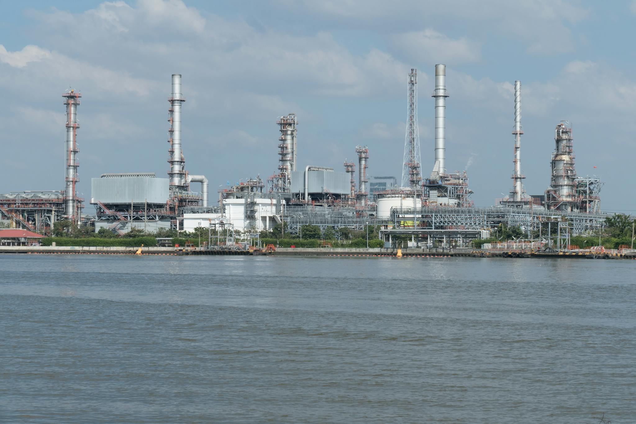 A large oil refinery complex next to the water with cloudy skies.