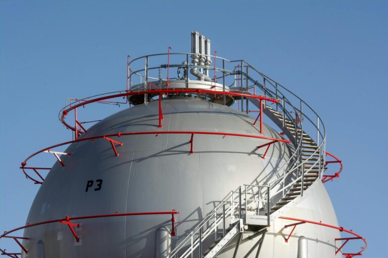 Close-up view of a large industrial gas storage sphere with a surrounding metal staircase.